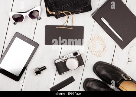 Concetto di viaggio - scarpe, jeans, tablet PC, fotocamera, notepad essentials e lavagna bianca sulla scrivania in legno Foto Stock