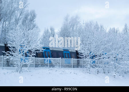 Wintery paesaggio con neve soffice e treni pendolari accelerando da, a Stoccolma, in Svezia. Foto Stock