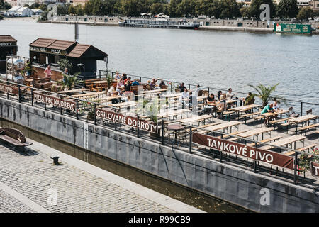 Praga, Repubblica Ceca - Agosto 23, 2018: persone sedute al tavolo di un caffè sul fiume Moldava a Praga. Vltava è il più lungo fiume entro il Cze Foto Stock