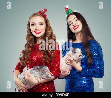 Felice Natale ragazze in party dress holding mini maiali. Natale e Anno Nuovo concetto delle donne Foto Stock