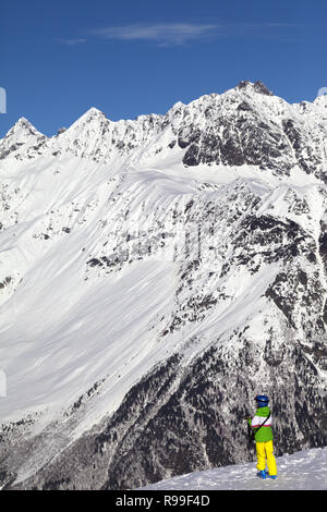 Poco sciatore indossando il casco rende la foto sulla sommità delle montagne innevate a Nizza il giorno sun. Montagne del Caucaso in inverno, Svaneti regione della Georgia. Foto Stock