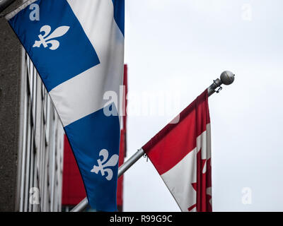 Bandiera del Quebec in piedi davanti alla bandiera ufficiale del Canada a Montreal, la principale città del Québec, la seconda più grande provincia del Canada, parlano francese Foto Stock