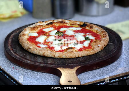 La pizza margherita con pomodoro, formaggio e basilico fresco collocato su un tagliere Foto Stock