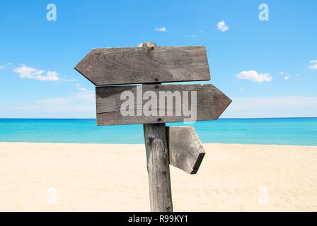 Estate destinazioni di viaggio opzioni. Direzione cartello stradale con frecce in legno sulla spiaggia e mare Foto Stock