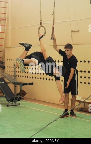 Kovrov, Russia. Il 13 ottobre 2013. Teen è impegnato su anelli di ginnastica in palestra della scuola Foto Stock