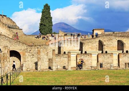 Pompei, Italia - 23 Ottobre 2018: turisti esplorare i resti dell'anfiteatro in antiche città di Pompei, con il Monte Vesuvio a distanza Foto Stock
