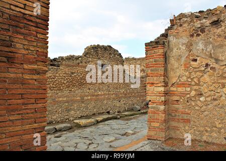 Una vista su ciò che sarebbe stata una strada, dall'interno dei resti di un edificio in antiche città di Pompei, Italia. Foto Stock