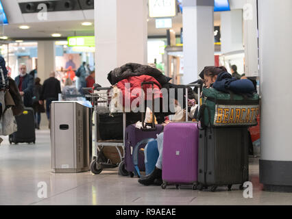 Berlino, Germania. Xxi Dec, 2018. I viaggiatori a sedersi su una panchina presso l'aeroporto di Tegel e attendere per il loro volo per essere chiamato. Credito: Paolo Zinken/dpa/Alamy Live News Foto Stock