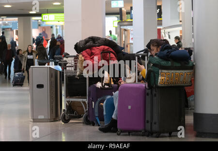 Berlino, Germania. Xxi Dec, 2018. I viaggiatori a sedersi su una panchina presso l'aeroporto di Tegel e attendere per il loro volo per essere chiamato. Credito: Paolo Zinken/dpa/Alamy Live News Foto Stock