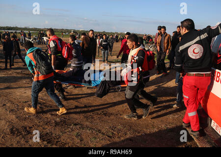 La striscia di Gaza, Territori palestinesi. Xxi Dec, 2018. I medici palestinesi portano un uomo ferito durante gli scontri con le truppe israeliane sul confine Gaza-Israel, a est di Gaza City, il 21 dicembre, 2018. Un ragazzo palestinese è stato ucciso venerdì e almeno 40 altri feriti durante gli scontri tra dimostranti palestinesi e soldati israeliani nella parte orientale della striscia di Gaza, vicino alla frontiera con Israele, i medici hanno detto. Credito: Xinhua/Alamy Live News Foto Stock