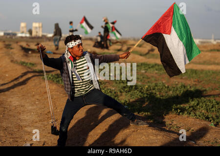 La striscia di Gaza, Territori palestinesi. Xxi Dec, 2018. Un manifestante palestinese utilizza una fionda di scagliare pietre contro le truppe israeliane sul confine Gaza-Israel, a est di Gaza City, il 21 dicembre, 2018. Un ragazzo palestinese è stato ucciso venerdì e almeno 40 altri feriti durante gli scontri tra dimostranti palestinesi e soldati israeliani nella parte orientale della striscia di Gaza, vicino alla frontiera con Israele, i medici hanno detto. Credito: Xinhua/Alamy Live News Foto Stock