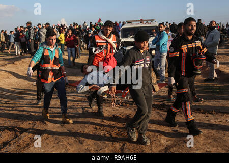 La striscia di Gaza, Territori palestinesi. Xxi Dec, 2018. I medici palestinesi portano un uomo ferito durante gli scontri con le truppe israeliane sul confine Gaza-Israel, a est di Gaza City, il 21 dicembre, 2018. Un ragazzo palestinese è stato ucciso venerdì e almeno 40 altri feriti durante gli scontri tra dimostranti palestinesi e soldati israeliani nella parte orientale della striscia di Gaza, vicino alla frontiera con Israele, i medici hanno detto. Credito: Xinhua/Alamy Live News Foto Stock