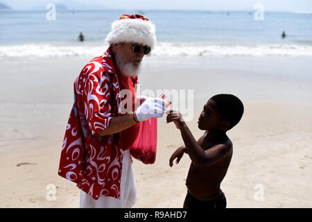 Rio De Janeiro, Brasile. Xxi Dec, 2018. Un uomo mascherato come un "tropicali Santa Claus' distribuisce dolciumi sulla spiaggia di Copacabana. Il tappo è stato messo su dal responsabile di Santa Claus nonostante le temperature al di sopra dei 30 gradi. Credito: Fabio Teixeira/dpa/Alamy Live News Foto Stock