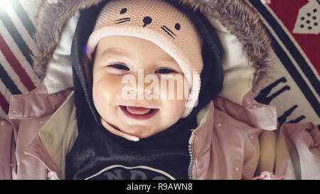 Ritratto di bambina in giacca invernale e hat sorridente su sfondo di Natale Foto Stock