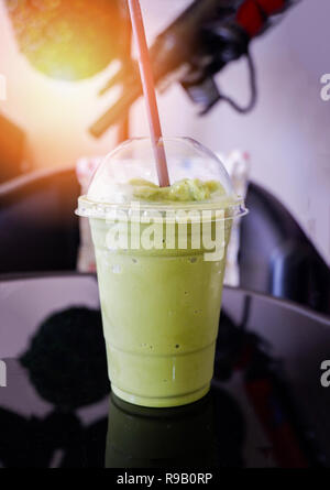 Schiuma di latte il tè verde smoothie / Iced green tea in plastica frullato di tazza di tè verde Matcha latte frappé e paglia sulla tavola in coffee shop Foto Stock