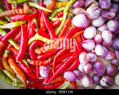 Peperoncino e lo scalogno background / peperoncino rosso guarnire le spezie in caldo e piccante di cuocere i cibi e Sbucciate gli scalogni sfondo vista superiore Foto Stock