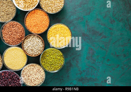 Piatto set di laici di bocce tonde con sani cereali, fagioli e semi sulla texture di sfondo di smeraldo. Vista dall'alto. Copia dello spazio. Cibo sano. Superfoods in cu Foto Stock