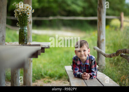 Carino fermer bello ragazzo cowboy in jeans godendo di giorno di estate in vita del villaggio con fiori in pelle da indossare mucca hat happyly sorridente Foto Stock