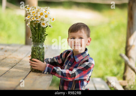 Carino fermer bello ragazzo cowboy in jeans godendo di giorno di estate in vita del villaggio con fiori in pelle da indossare mucca hat happyly sorridente Foto Stock