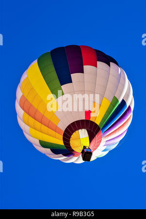 Colorate mongolfiere contro un profondo blu del cielo e del deserto scogliere. Foto Stock