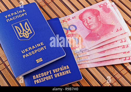 Passaporto ucraino e yuans closeup sullo sfondo del tappetino di bambù Foto Stock