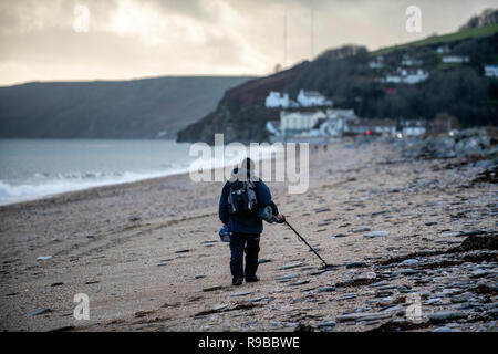 Metal detectorist su Slapton sands beach nel Devon, Regno Unito. Foto Stock