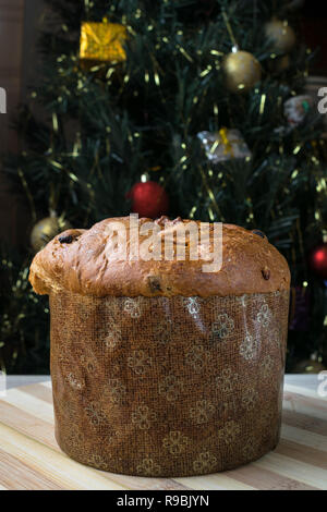 Panettone natalizio torta con lo sfondo di un albero di Natale. Tipico dolce di Natale Foto Stock