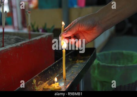 Buddisti di rendere merito,posizionando una candela accesa e incenso illuminato con candele telaio sull altare del Buddha a tempio. Messa a fuoco selettiva. Foto Stock