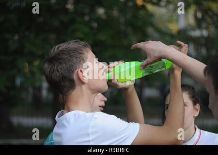 Kovrov, Russia. Il 30 maggio 2014. Teen beve l'acqua da una bottiglia di plastica durante il giocare a pallavolo in schoolyard Foto Stock