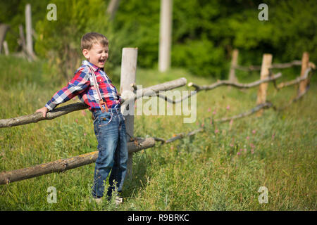 Carino fermer bello ragazzo cowboy in jeans godendo di giorno di estate in vita del villaggio con fiori in pelle da indossare mucca hat happyly sorridente Foto Stock