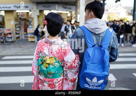 Un giovane giapponese giovane donna in costume tradizionale, in attesa di attraversare la strada, Kyoto, Giappone Foto Stock