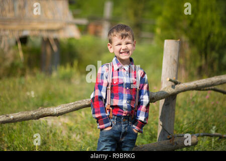 Carino fermer bello ragazzo cowboy in jeans godendo di giorno di estate in vita del villaggio con fiori in pelle da indossare mucca hat happyly sorridente Foto Stock