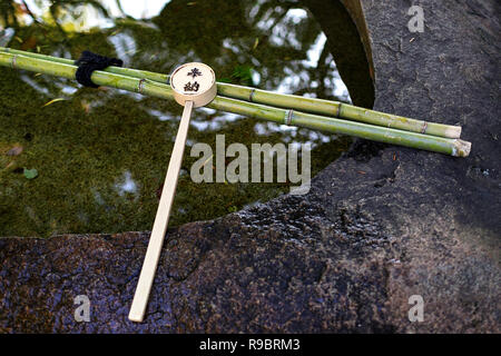 Un mestolo di legno, utilizzato per purfication, appoggia all'entrata di un giardino in uno dei molti templi a Kyoto, Giappone Foto Stock