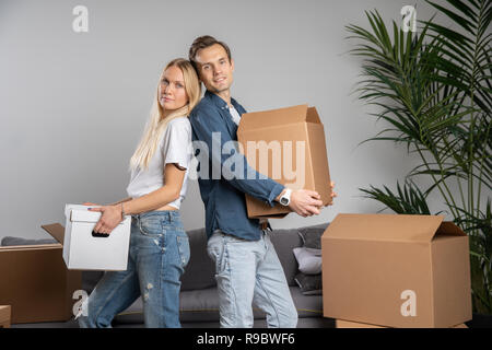 Foto della giovane donna e uomo in piedi tra le scatole di cartone Foto Stock