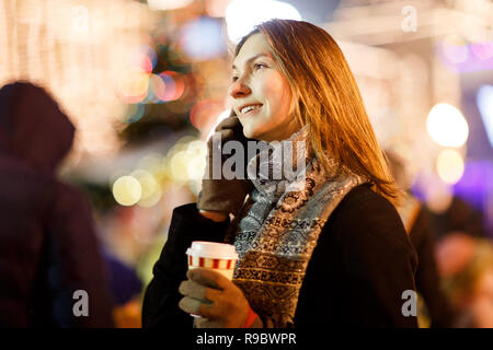 Foto di donna con vetro e telefono in mani in serata per camminare Foto Stock