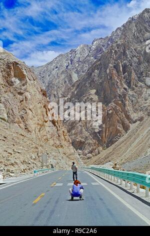 Turisti viaggiano lungo la Karakoram Highway nello Xinjiang Uyghur Regione autonoma, Cina, con lo splendido paesaggio di montagna della Valle dello sfondo. Foto Stock