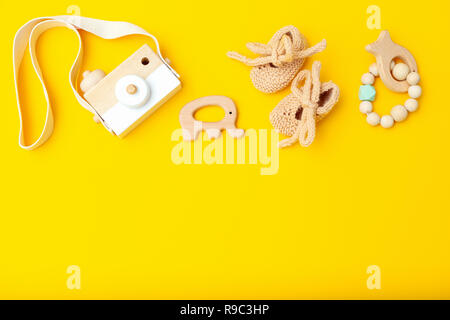 Giocattoli di legno e scarpe per bambini su uno sfondo giallo. Spazio di copia Foto Stock