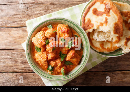 Il cibo indiano piccante karhai pollo in salsa di pomodoro da vicino e naan sul tavolo. parte superiore orizzontale vista da sopra, stile rustico Foto Stock