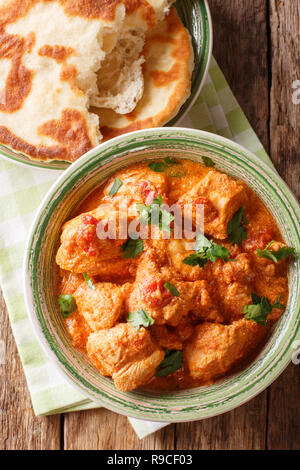 Karhai indiano pollo in salsa piccante di close-up servite con pane naan sul tavolo. Verticale in alto vista da sopra Foto Stock