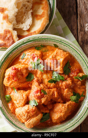 Karhai pollo in una piccante salsa di pomodoro closeup servita con pane naan su un tavolo. Verticale in alto vista da sopra Foto Stock