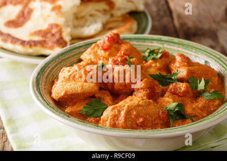 Il cibo indiano piccante karhai pollo in salsa di pomodoro da vicino e naan sul tavolo. orizzontale, stile rustico Foto Stock