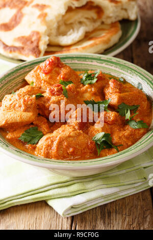 Karhai indiano pollo in salsa piccante di close-up servite con pane naan sul piano verticale. Foto Stock