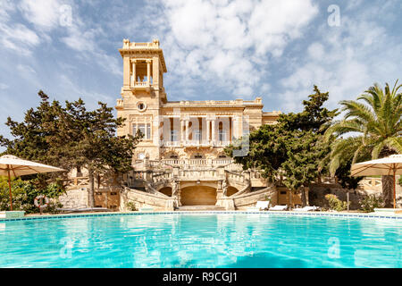 St Julians, Malta. 1920s art nouveau mansion Villa Rosa costruita nel ​park di St Julian's town dall architetto Andrea Vassallo, Malta, riflette in un azzurro piscina. Foto Stock