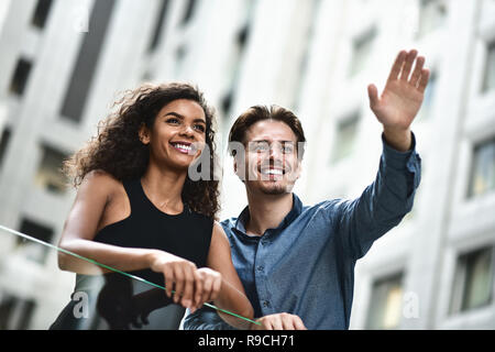 Felice coppia internazionale hanno una conversazione in città. Razza mista donna e uomo caucasico. Foto Stock