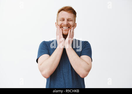 Infine barba crescente. Il piacere gioioso felice bello maschio maturo con zenzero toccando i capelli di setole e sorridente largamente con gli occhi chiusi, essendo sul cielo di felicità e di emozioni positive Foto Stock
