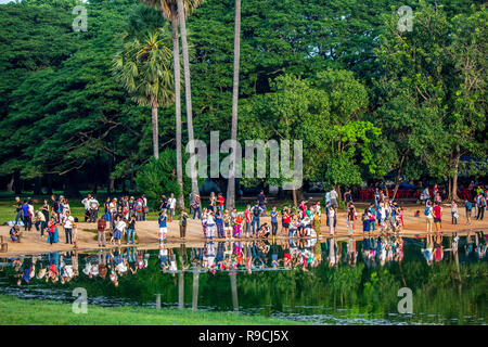 I turisti guarda sunrise attraverso un laghetto con alberi verdi in background a Angkor Wat tempio complesso in Siem Reap, Cambogia. Foto Stock