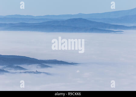 La nebbia di riempimento di una valle in Umbria (Italia), con strati di montagne e colline e varie sfumature di blu Foto Stock