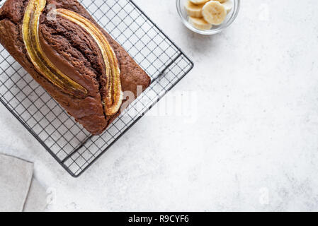 Cioccolato artigianale pane alla banana su sfondo bianco, copia dello spazio. Un sano pane alla banana o torta con cioccolato fondente per colazione, vista dall'alto. Foto Stock