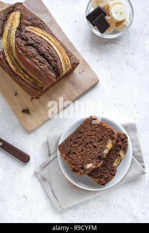 Cioccolato artigianale pane alla banana su sfondo bianco, copia dello spazio. Un sano pane alla banana o torta con cioccolato fondente per colazione, vista dall'alto. Foto Stock