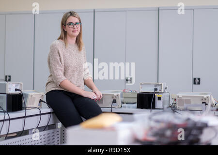 Ritratto di giovane e bella studentessa seduta sul tavolo al laboratorio di elettronica classroom Foto Stock